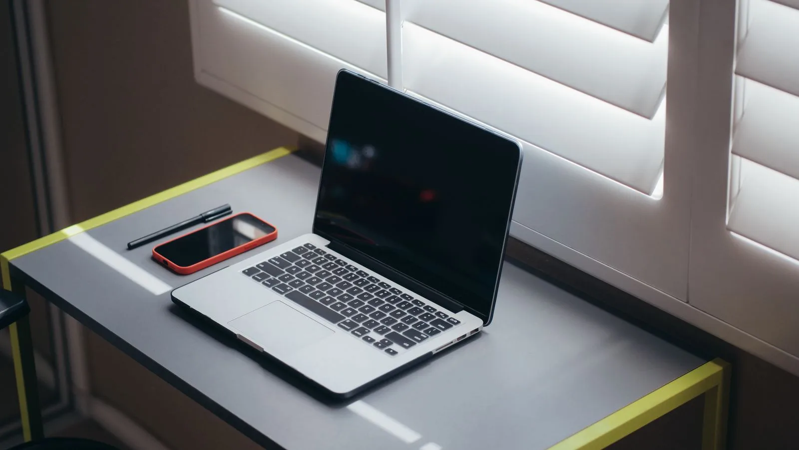 A laptop and phone sit on a desk.
