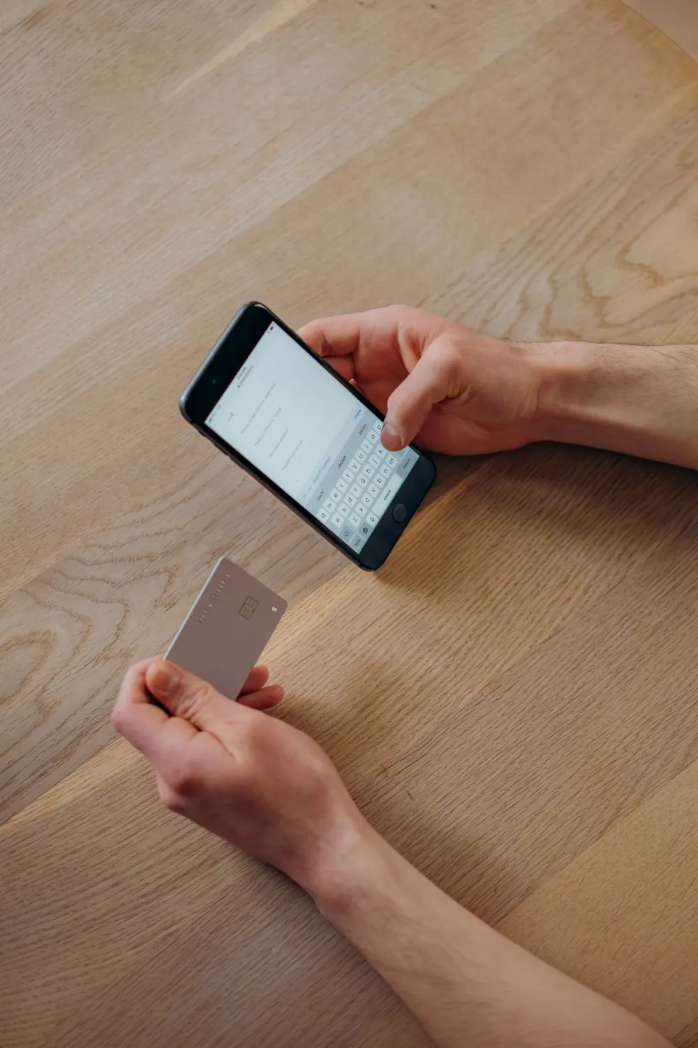 A person holds a bank card while using a phone.